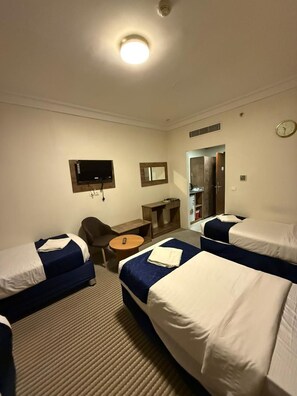 A hotel room with two single beds, a desk, a chair, a television, and a wardrobe.