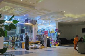 Un interior moderno con un escaparate de vidrio, diversas prendas de vestir exhibidas y una persona vestida con traje tradicional.