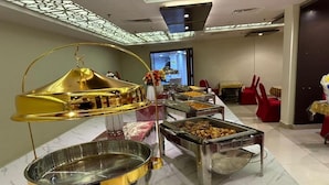 A buffet setup with multiple serving stations, a decorative golden centerpiece, and a modern interior design.