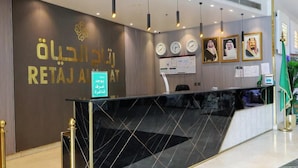 A reception desk with a dark marble top, a wall-mounted clock, and framed portraits.