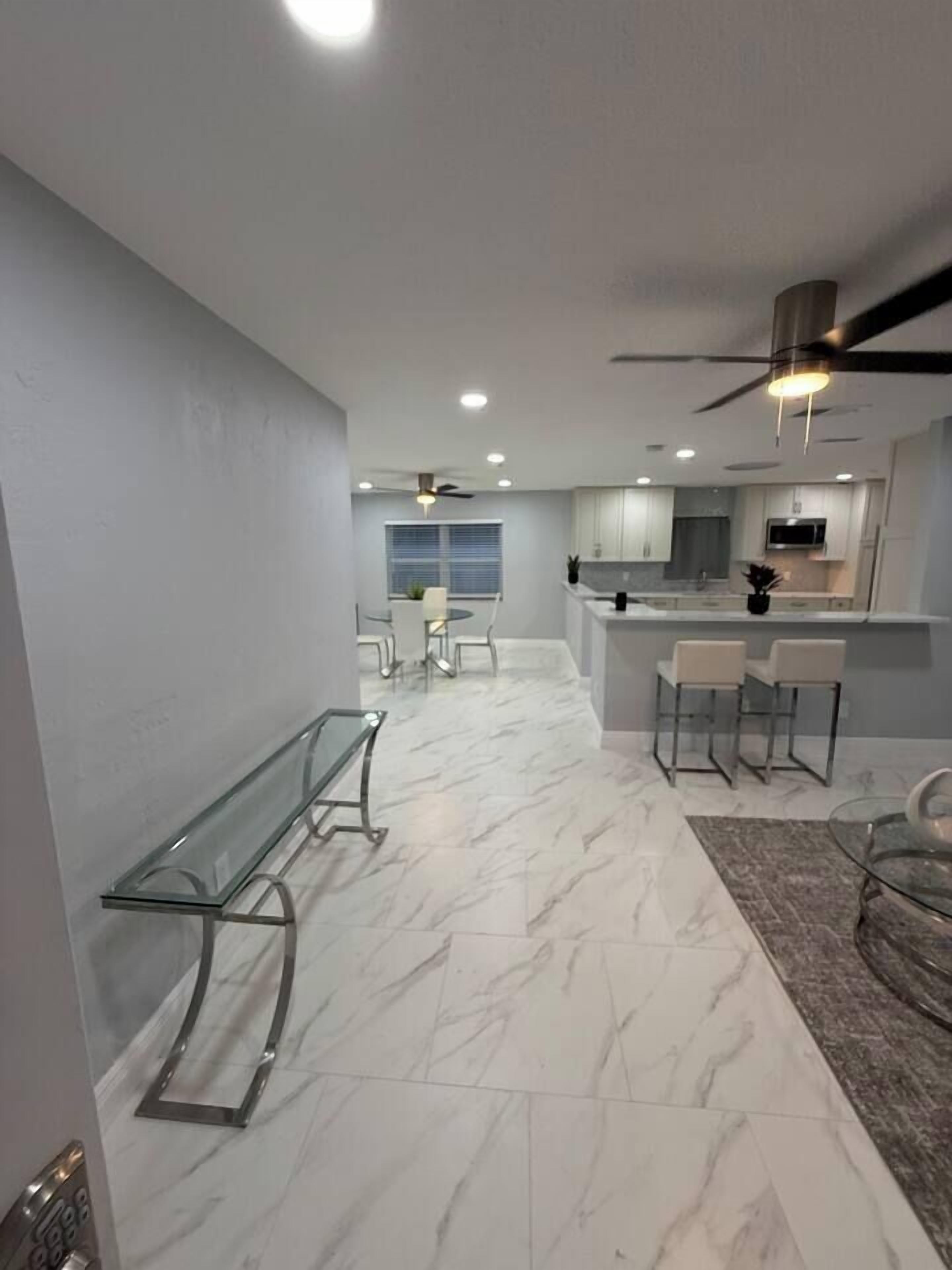 A modern kitchen with a bar area, marble flooring, and contemporary furniture.