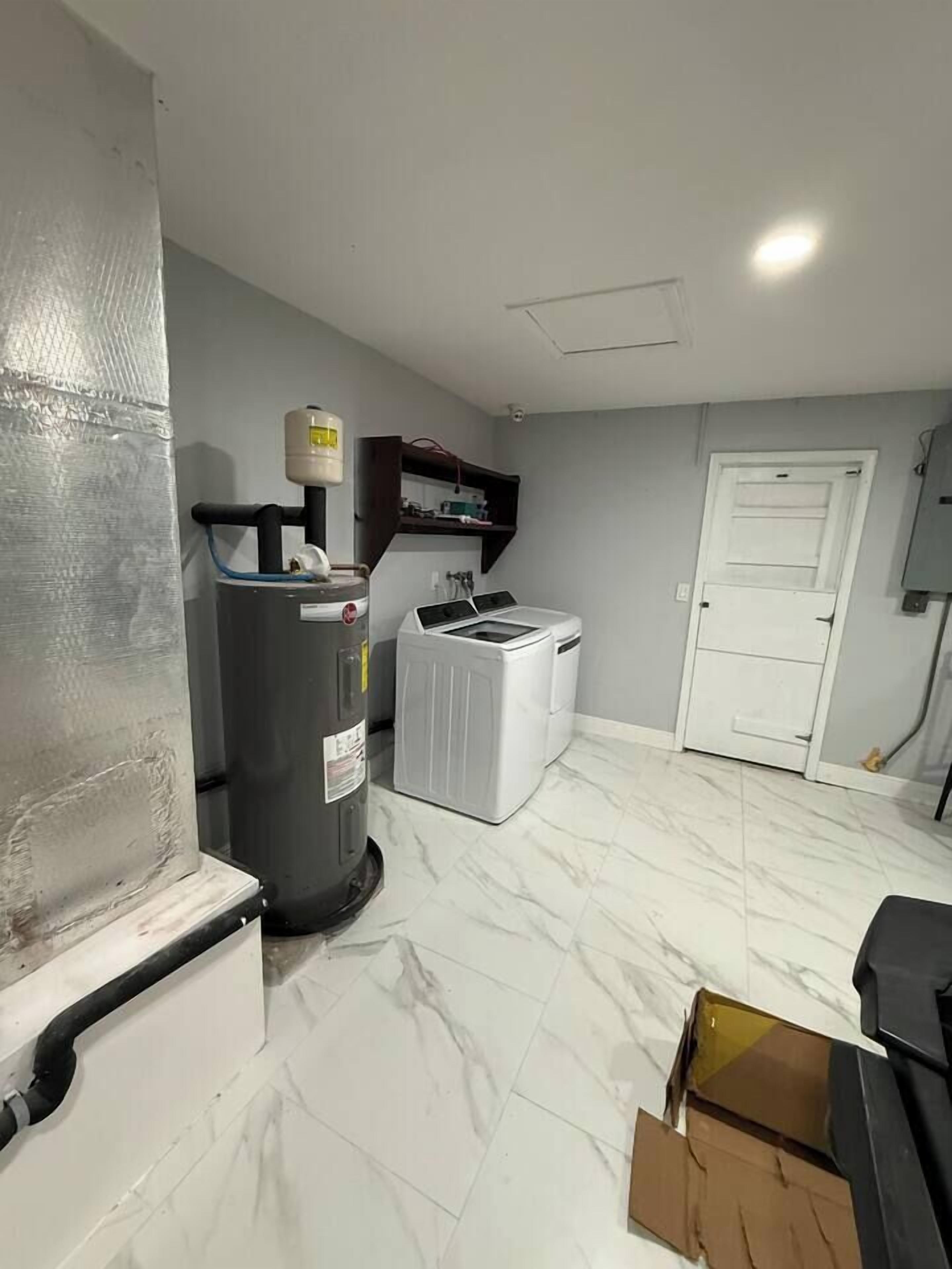 A room with a water heater, a washing machine, and a door.