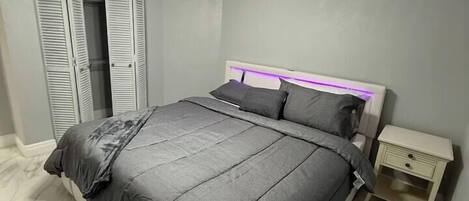 A bedroom with a bed, a nightstand, a ceiling fan, and a wardrobe with sliding doors.