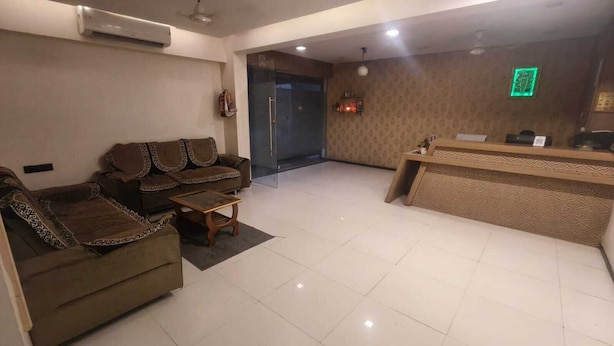 Una hall d'albergo con una reception, un divano e un pavimento piastrellato.