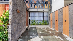A modern building with a stone facade, a wooden door, and a window with curtains. - Kanasu Villa by Exotic Bali Properties (Canggu)