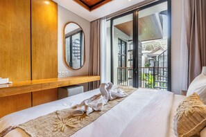 Ein Hotelzimmer mit einem großen Bett, einem Holztisch, einem Spiegel und Blick auf den Außenbalkon.