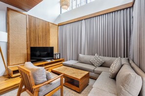 Ein modernes Wohnzimmer mit einer Couch, einem Fernseher, einem Couchtisch aus Holz und einem Sessel.