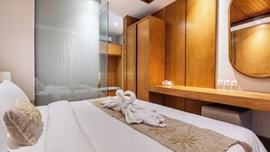 A hotel room with a bed, a wooden wardrobe, a mirror, and a bedside table with a lamp. - Kanasu Villa by Exotic Bali Properties (Canggu)