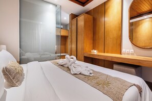 A hotel room with a bed, a wooden wardrobe, a mirror, and a bedside table with a lamp. - Kanasu Villa by Exotic Bali Properties (Canggu)