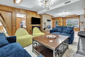 Una sala de estar moderna con un televisor de pantalla plana, una chimenea y un sofá azul grande.