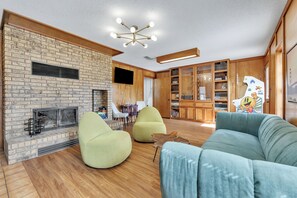 Ein modernes Wohnzimmer mit Kamin aus Backstein, einem Flachbildfernseher und einem hölzernen Bücherregal.