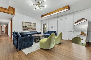 A modern living room with a sofa, chairs, a coffee table, and a large mirror. - Southside: Swimming Pool/Air Hockey/PacMan/5BRs (College Station, TX)