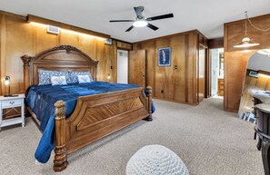 Ein Schlafzimmer mit einem hölzernen Bett, einem Deckenventilator und einem Nachttisch.