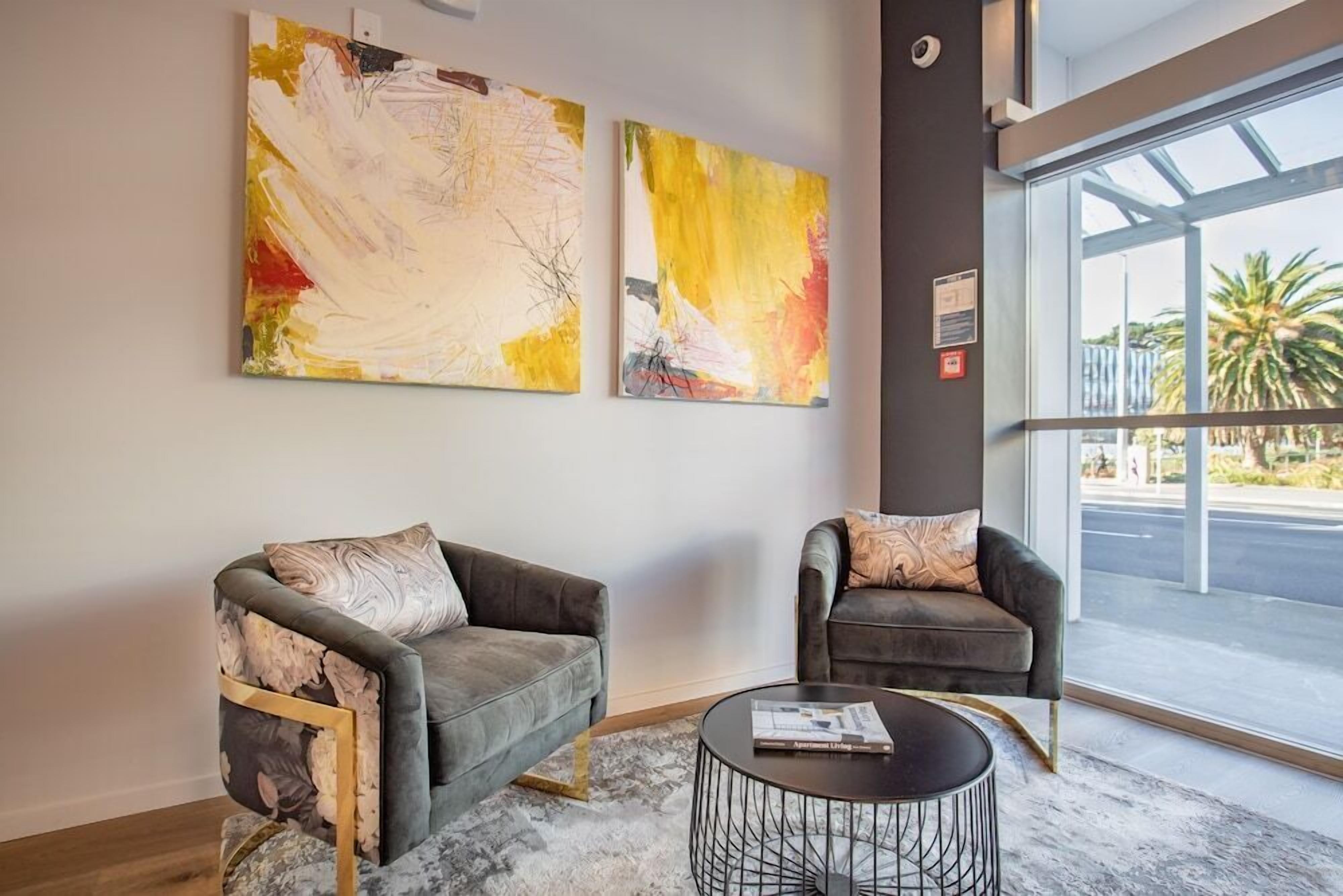 A modern living room with two sofas, a coffee table, and abstract paintings on the wall.
