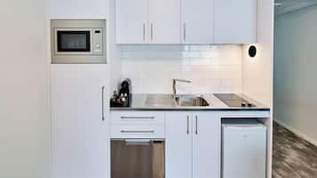A modern kitchen with white cabinetry, a built-in microwave, a sink, and a dishwasher.