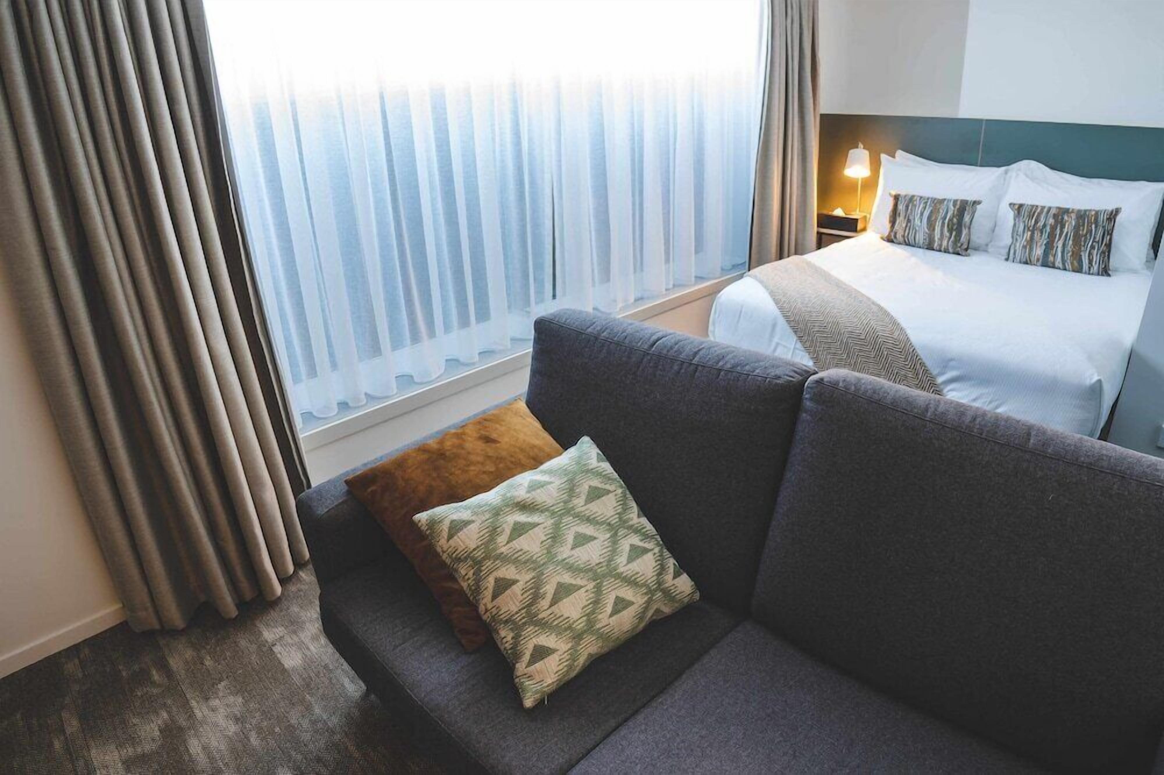 Ein Hotelzimmer mit einem Bett, einem Sofa und einem fensterbepflanzten Fenster.