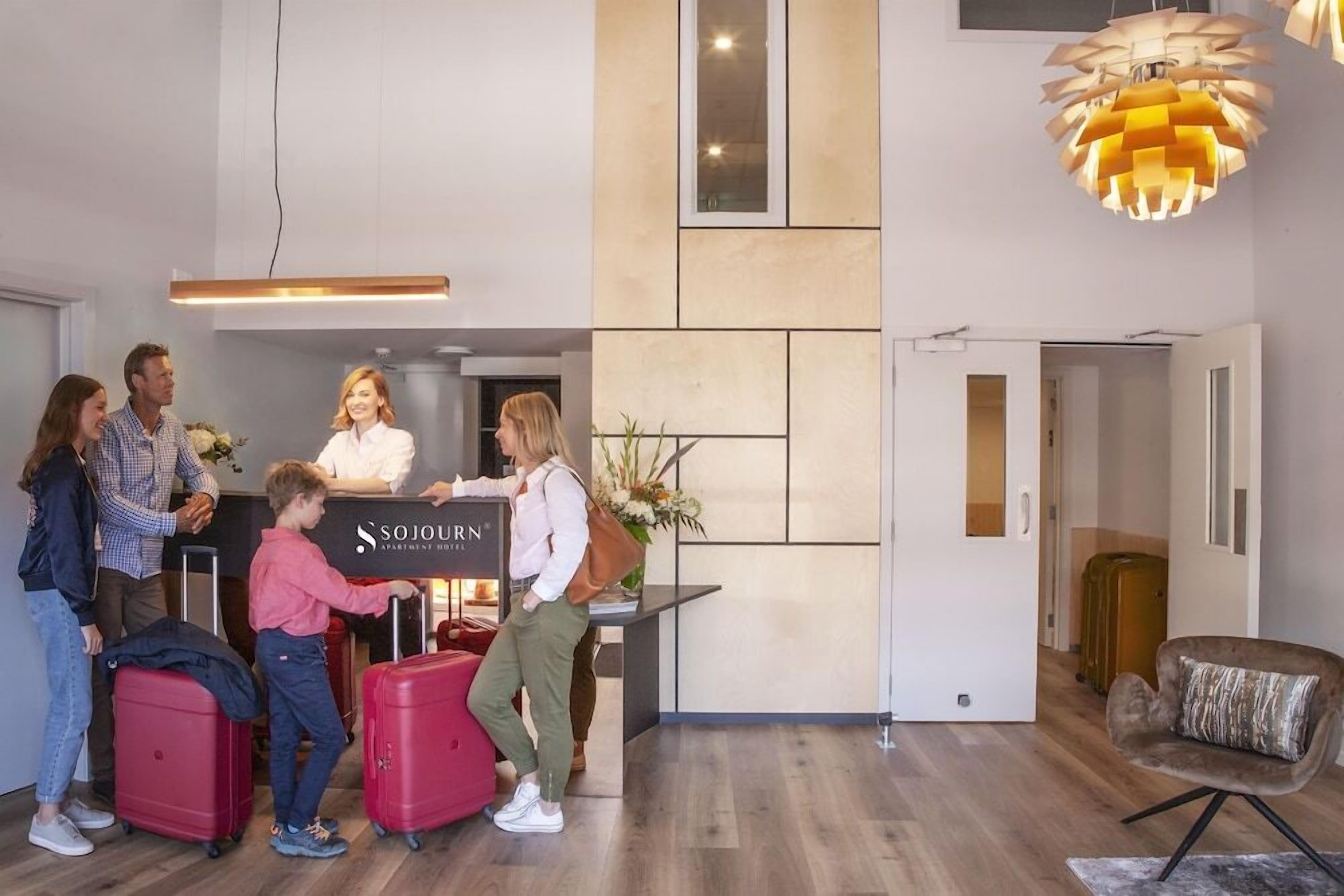 A reception area with a desk, a sign that reads 'SOJOURN,' and a modern interior design.