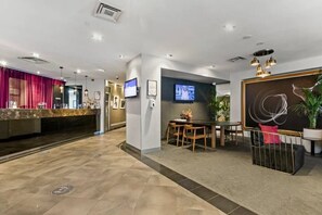 A hotel lobby with a reception desk, seating area, and a television screen. - Apartment 1112 ‘The middle of everywhere’ (Southbank)