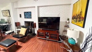 A living room with a fireplace, television, and a painting on the wall.