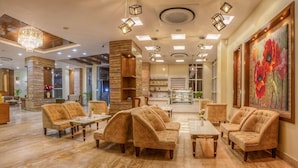 A spacious lobby with a marble floor, plush seating, and a large floral painting. - Regenta Place Sabrina Kathmandu (Burhanilkantha)