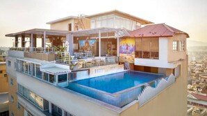 A multi-story building with a rooftop swimming pool, outdoor seating, and a mural. - Regenta Place Sabrina Kathmandu (Burhanilkantha)