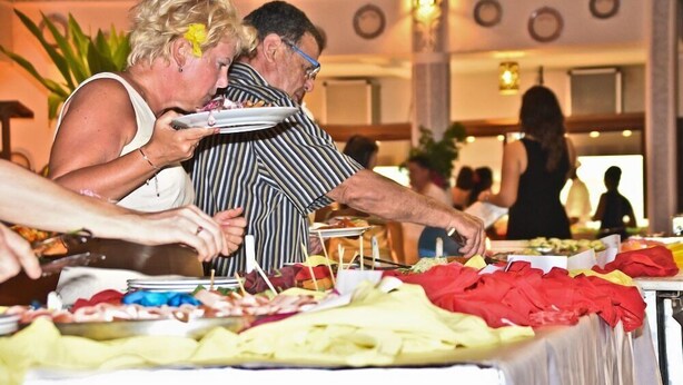 Ein reichhaltiges Buffet mit verschiedenen Speisen sowie ein Essbereich mit Tischen und Stühlen.