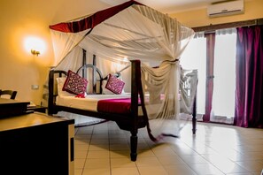 A room with a bed under a canopy, a desk, a chair, and a window with curtains. - JAZ Adonia Beach Resort (Uroa)