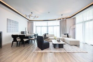 Uma sala de estar moderna com área de jantar, apresentando um sofá, cadeiras, uma mesa de centro e um lustre.