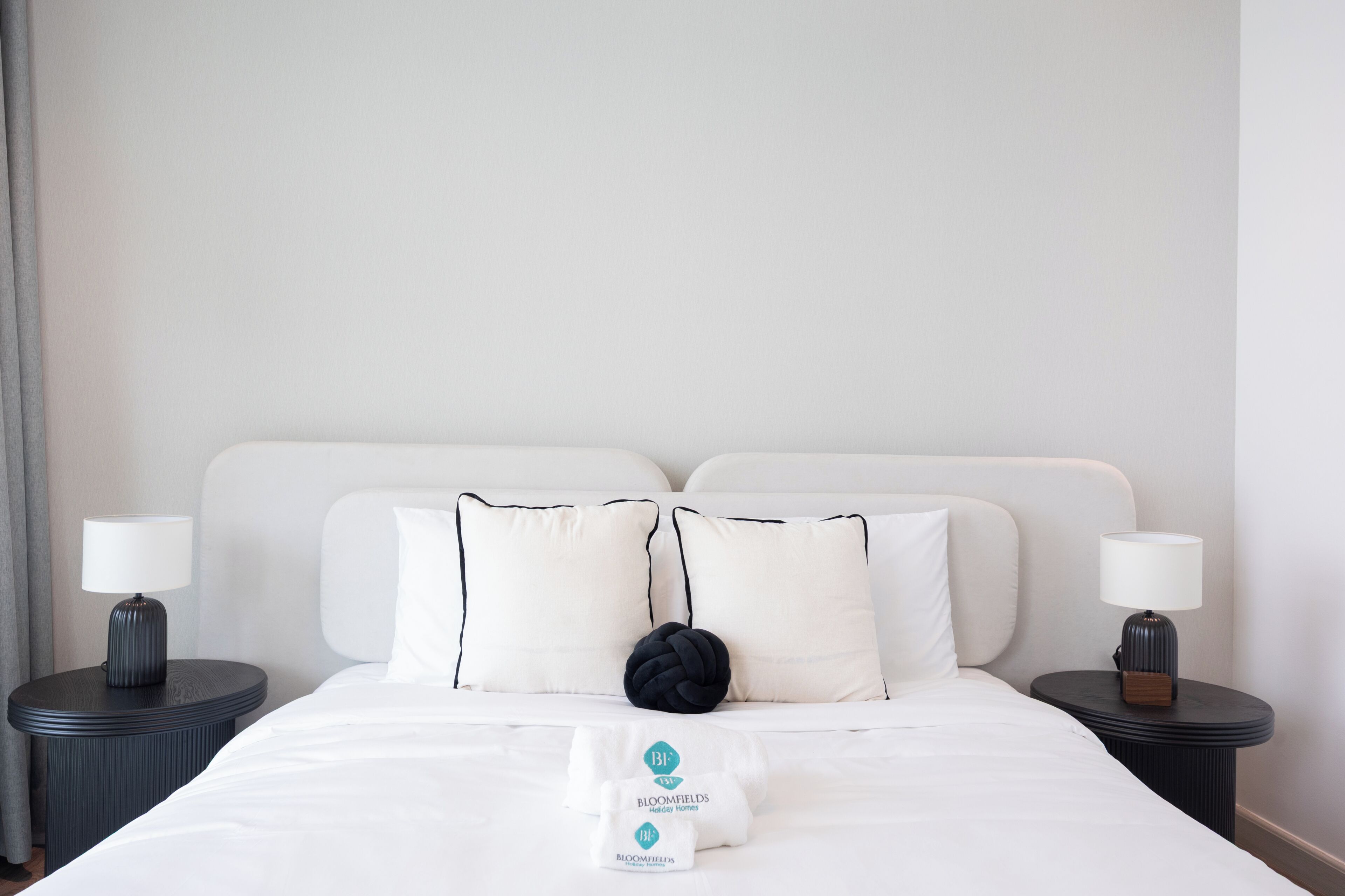 A hotel room with a large bed, two bedside tables, and a nightstand.