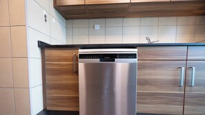 A stainless steel dishwasher in a kitchen with wooden cabinets and tiled walls. - Bloomfields 3BR plus Maid in Beach Tower (Abu Dhabi)
