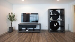 A modern living room with a flat-screen TV, a dark console table, and a decorative shelving unit with books and vases. - Bloomfields 3BR plus Maid in Beach Tower (Abu Dhabi)