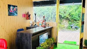 Una habitación con techo de madera, una zona de bar con televisor, una silla roja y plantas en macetas.