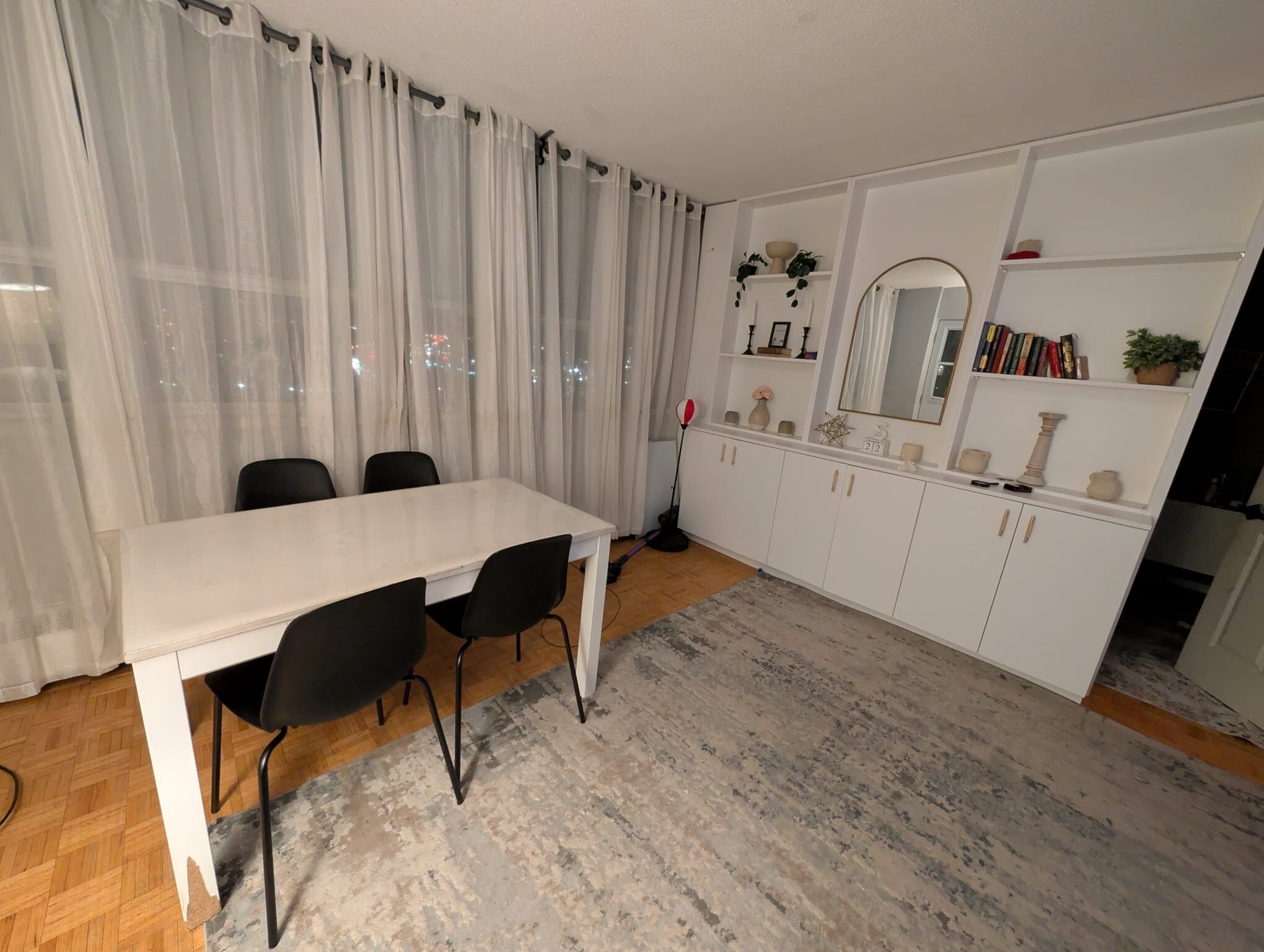 Une cuisine moderne avec des meubles blancs, un plan de travail blanc et un grand miroir au-dessus de l’évier.