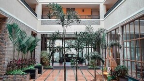 Ein mehrgeschossiges Atrium mit einem zentralen, offenen Bereich, umgeben von Balkonen und Kübelpflanzen.