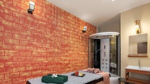 Ein Spa-Raum mit Massagetisch, Dusche und Schminktisch mit Spiegel.