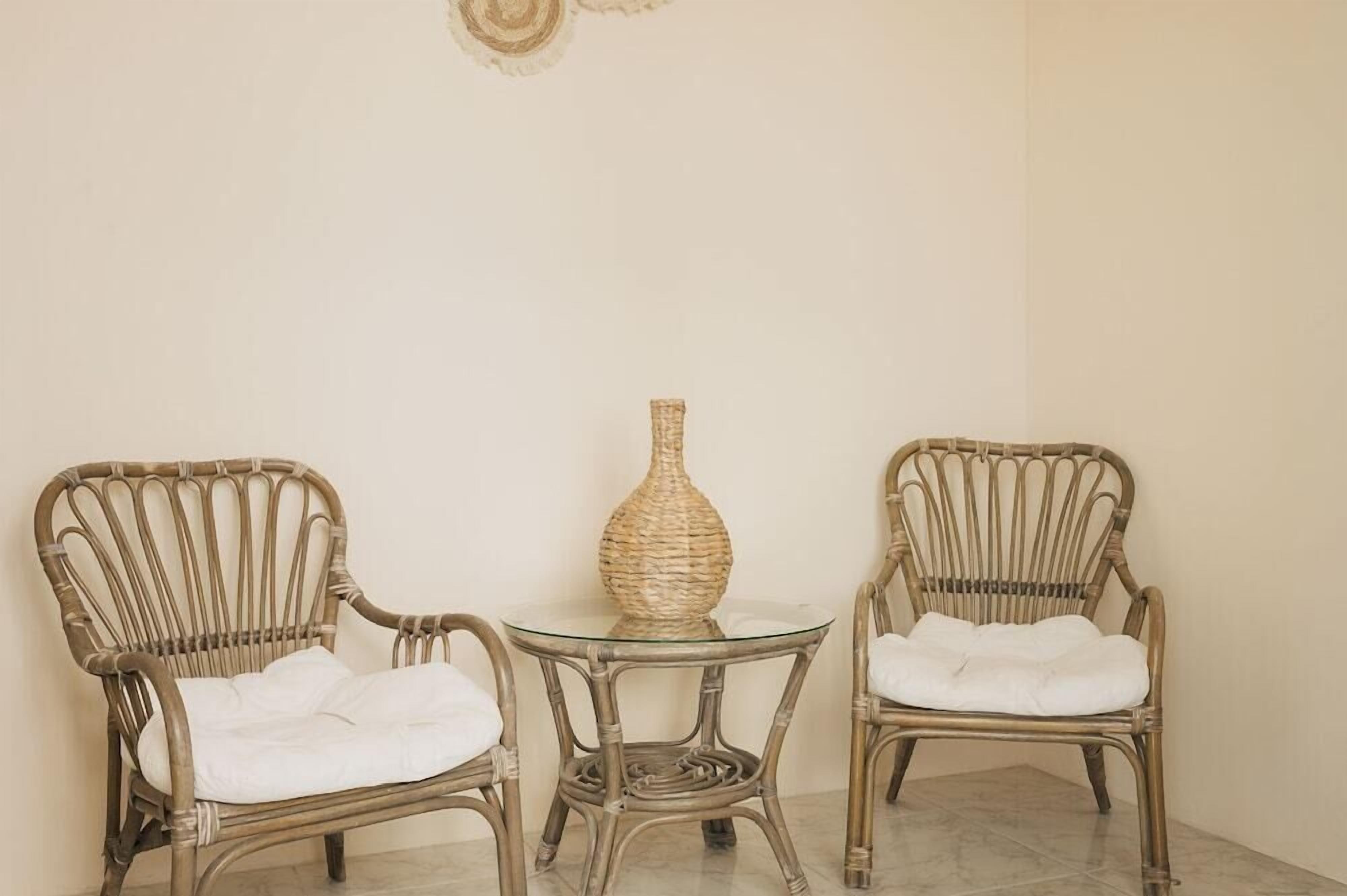 Two wicker chairs with cushions, a glass table, and a woven vase.