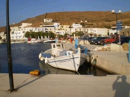 Un puerto costero con barcos amarrados, cielo despejado y edificios al fondo.