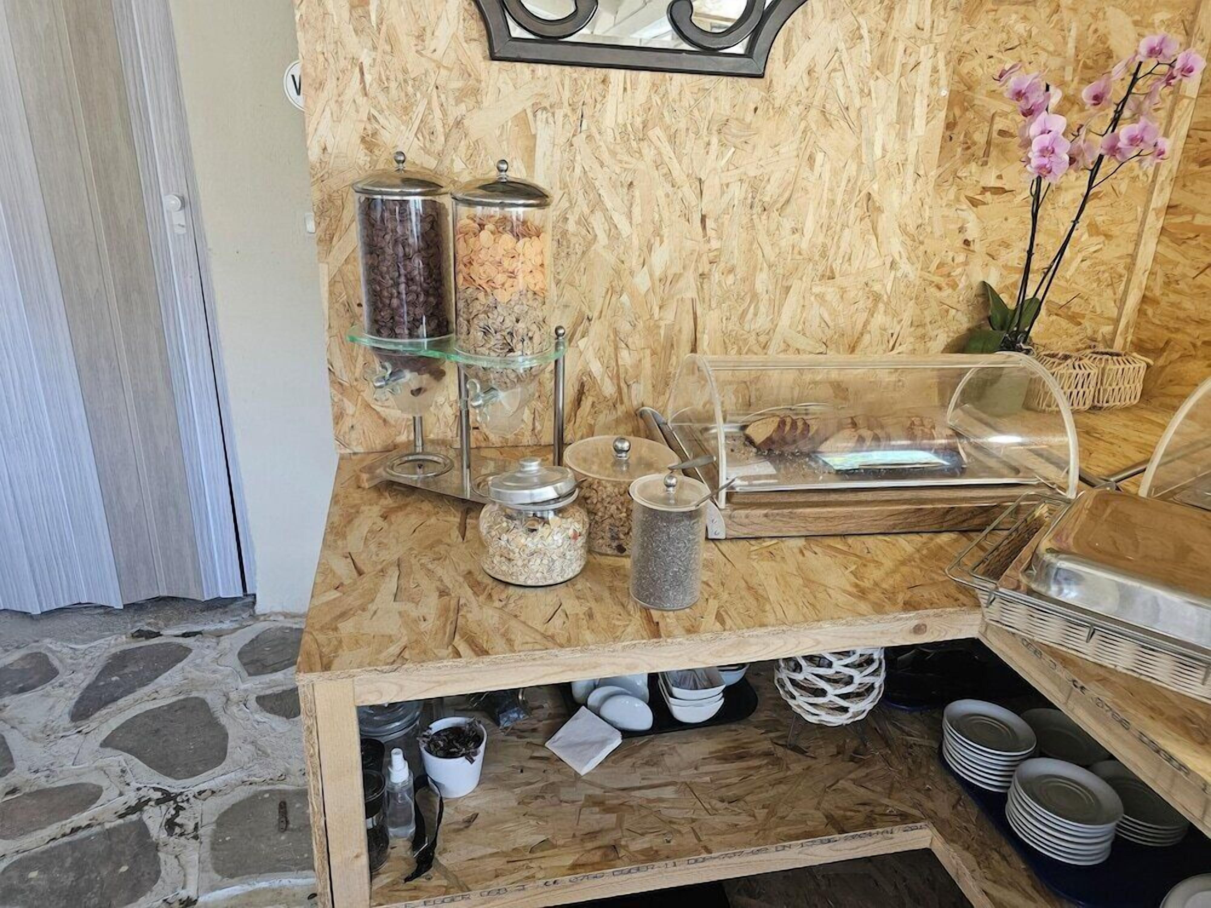 A wooden buffet setup with glass containers, a coffee machine, and a decorative orchid plant.