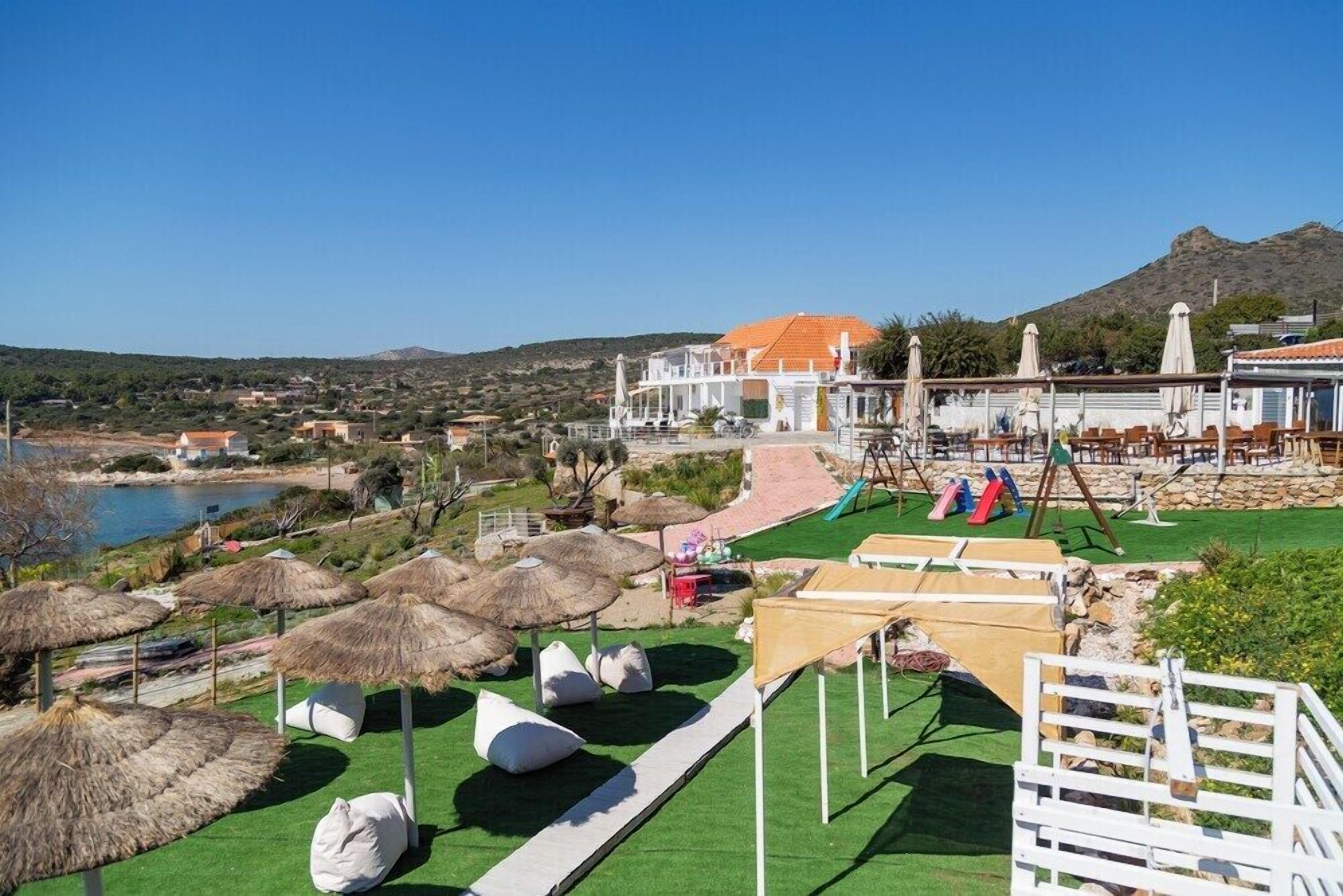 Un resort con piscina, zona de estar al aire libre y vistas al mar y a las colinas.