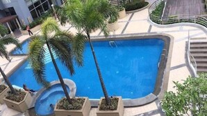 A swimming pool surrounded by palm trees and a building in the background.