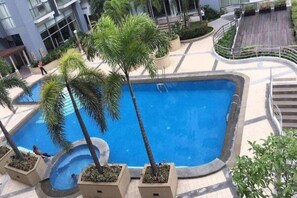 A swimming pool surrounded by palm trees and a building in the background.