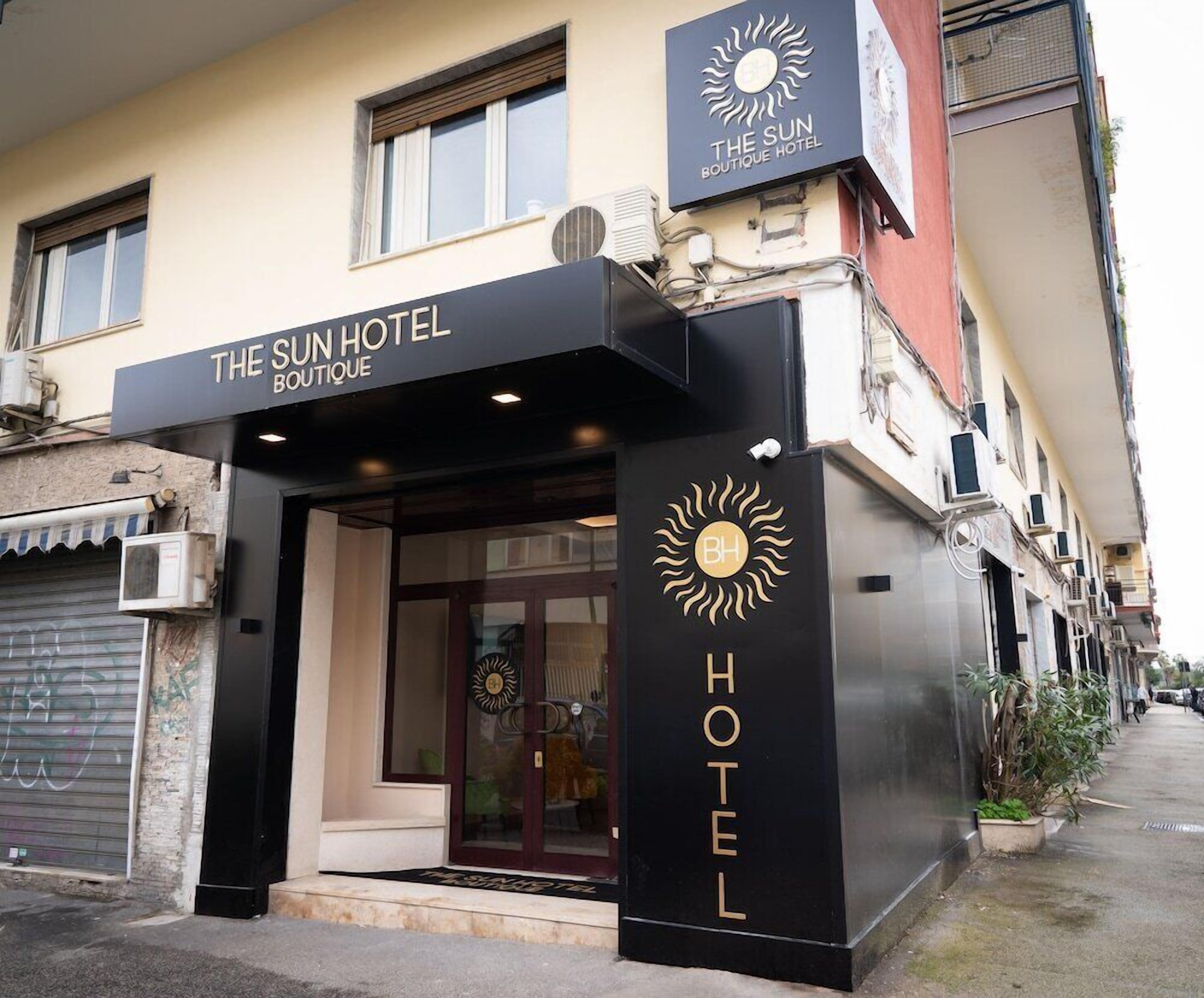 A hotel entrance with a sign reading 'The Sun Hotel Boutique.'