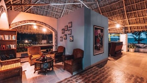 A room with a thatched roof, wicker furniture, and framed pictures on the walls. - F-zeen Boutique Hotel Zanzibar (Uroa)