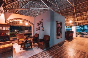 A room with a thatched roof, wicker furniture, and framed pictures on the walls. - F-zeen Boutique Hotel Zanzibar (Uroa)