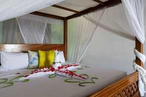 A bed with a canopy, pillows, and a decorative item on the headboard. - F-zeen Boutique Hotel Zanzibar (Uroa)