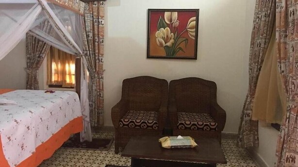 Una habitación con una cama, dos sillones, una mesa de centro y un cuadro en la pared.