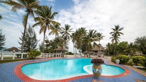 A swimming pool with a tiled edge, surrounded by palm trees and a clear sky. - F-zeen Boutique Hotel Zanzibar (Uroa)