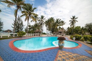 A swimming pool with a tiled edge, surrounded by palm trees and a clear sky. - F-zeen Boutique Hotel Zanzibar (Uroa)