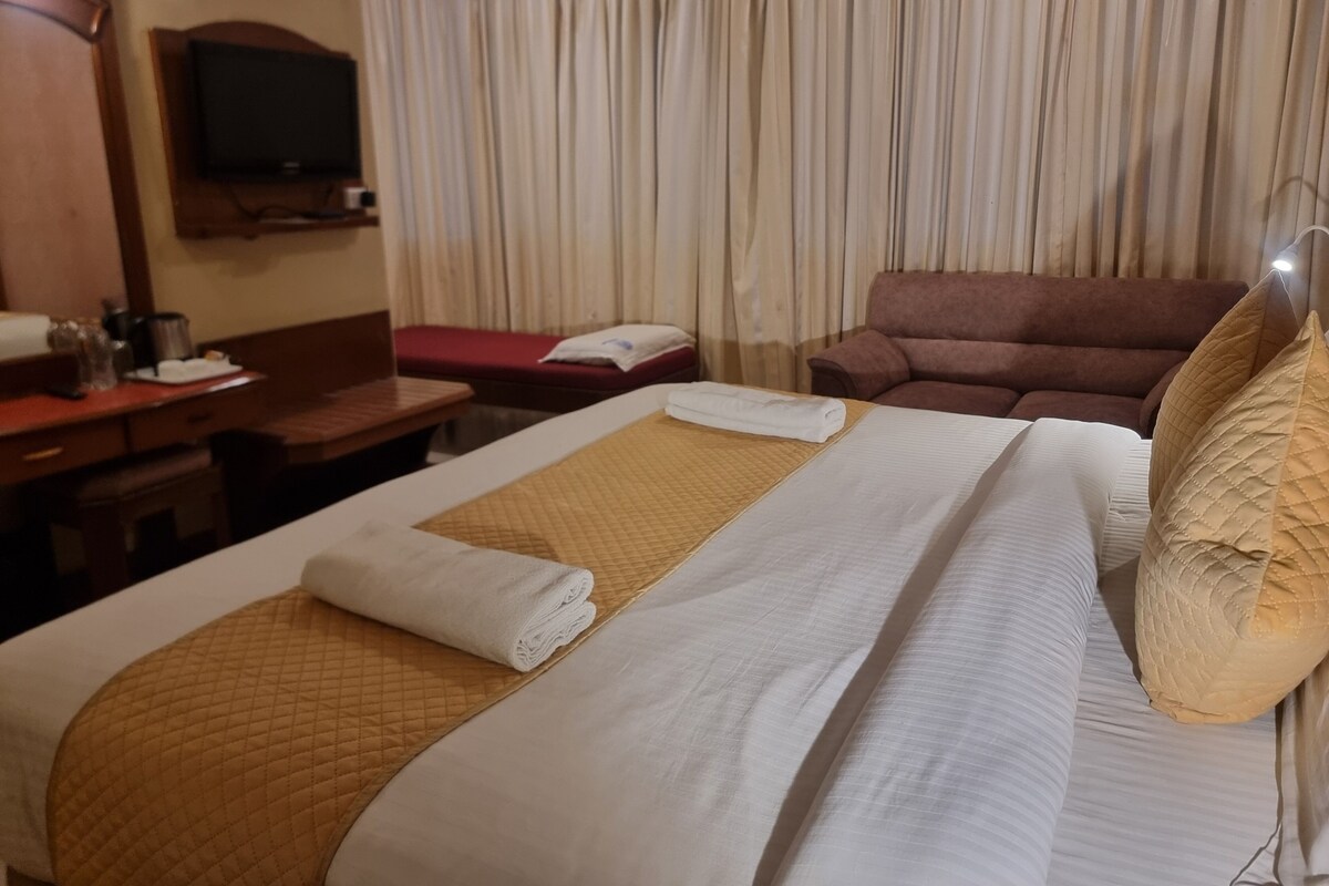 A hotel room with a bed, a desk, a television, and a couch.