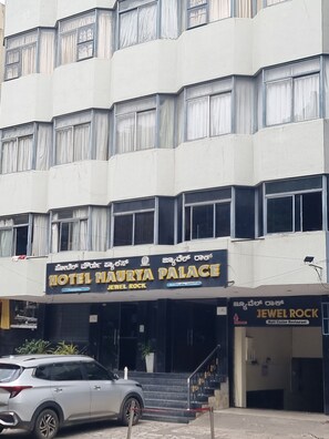 A multi-story building with a sign for 'Hotel Maurya Palace' and 'Jewel Rock' restaurant.